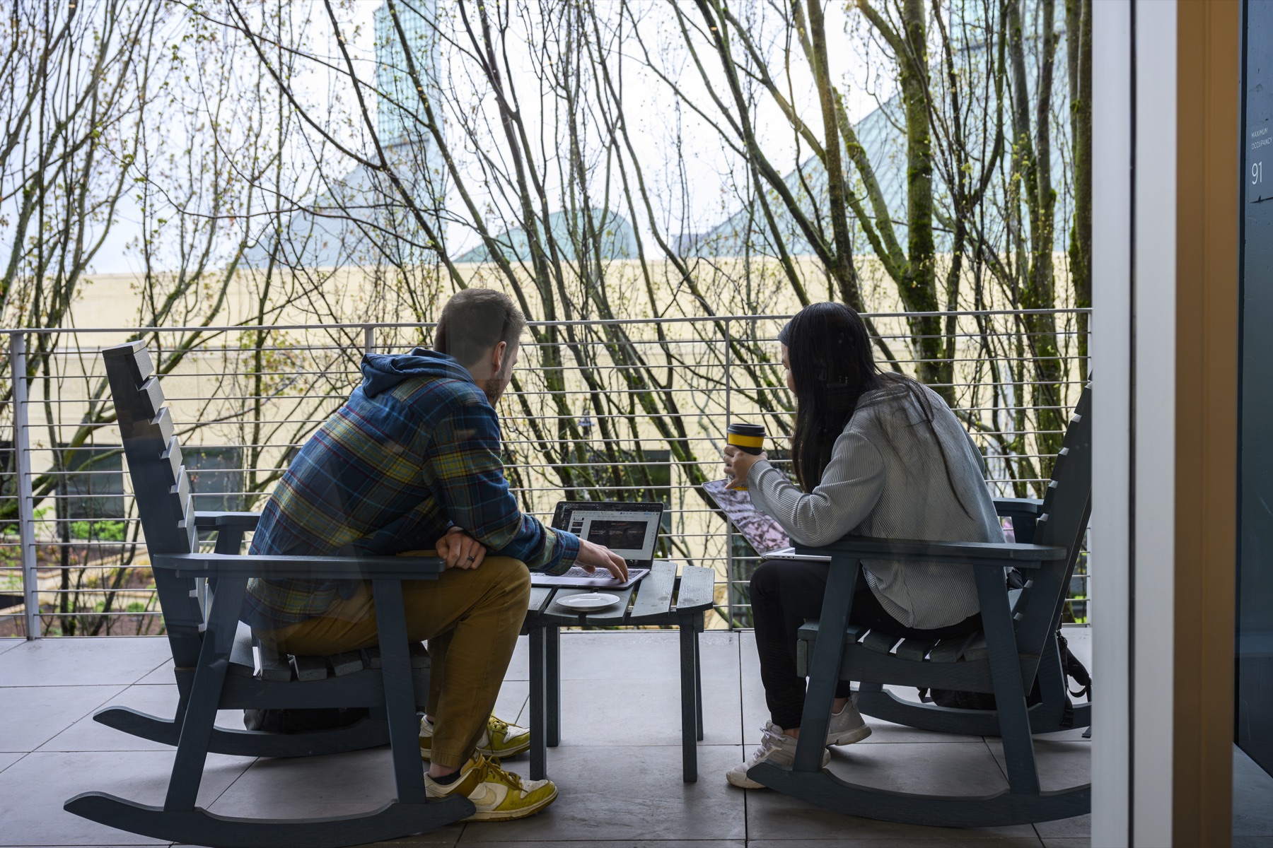 Two attendees working on laptops on an outdoor balcony